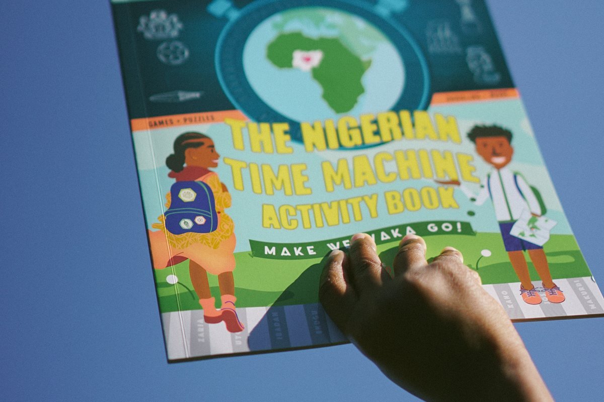 A child holding the activity book up against a blue sky